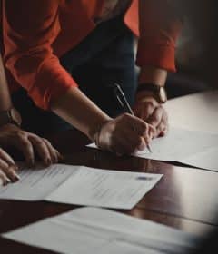 person in orange long sleeve shirt writing on white paper