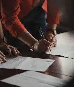 person in orange long sleeve shirt writing on white paper